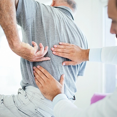 Man In Grey Shirt Pointing To Back Pain
